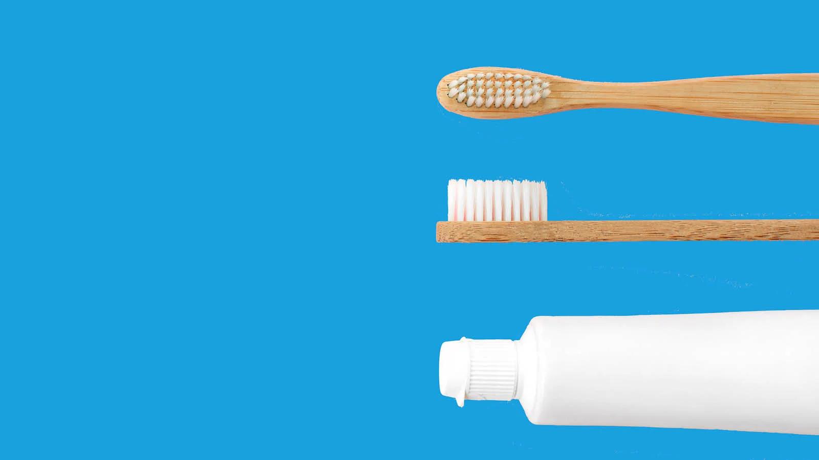 Two wooden toothbrushes and a plain white toothpaste tube