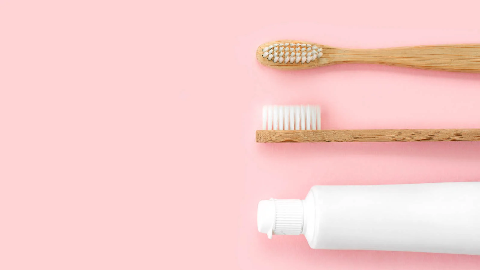 Two wooden toothbrushes and a plain white toothpaste