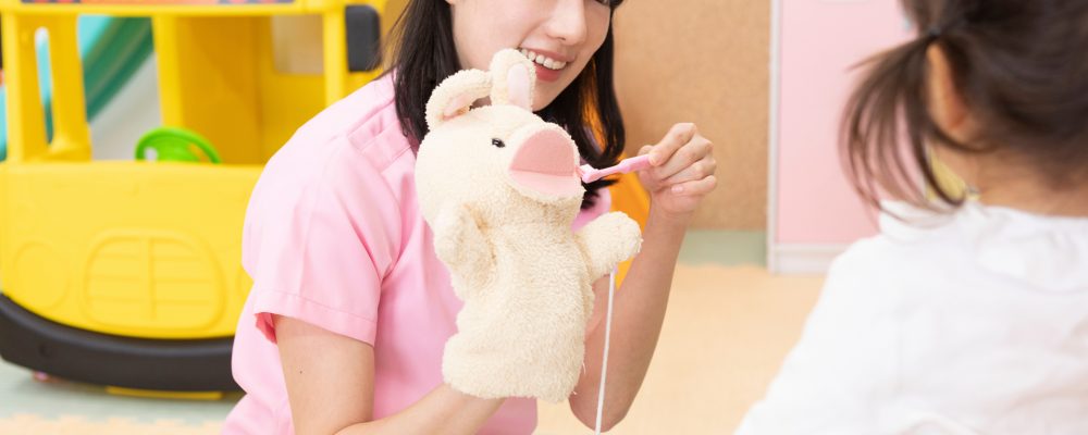 Teacher using a puppet to teach a child how to brush their teeth