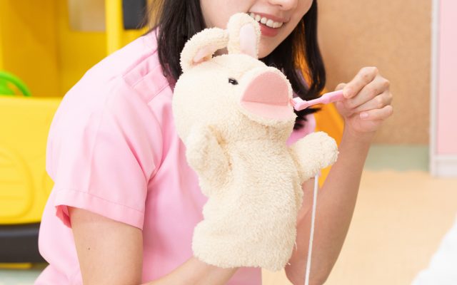 Teacher using a puppet to teach a child how to brush their teeth