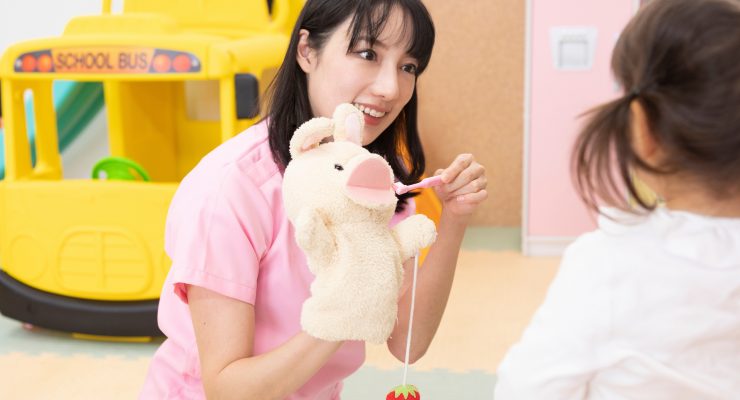 Teacher using a puppet to teach a child how to brush their teeth