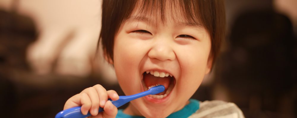 Image of child brushing his teeth and smiling