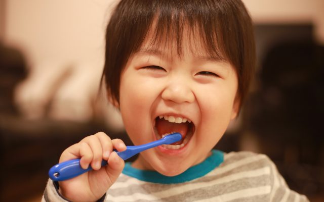 Image of child brushing his teeth and smiling