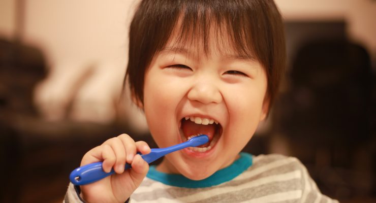 Image of child brushing his teeth and smiling